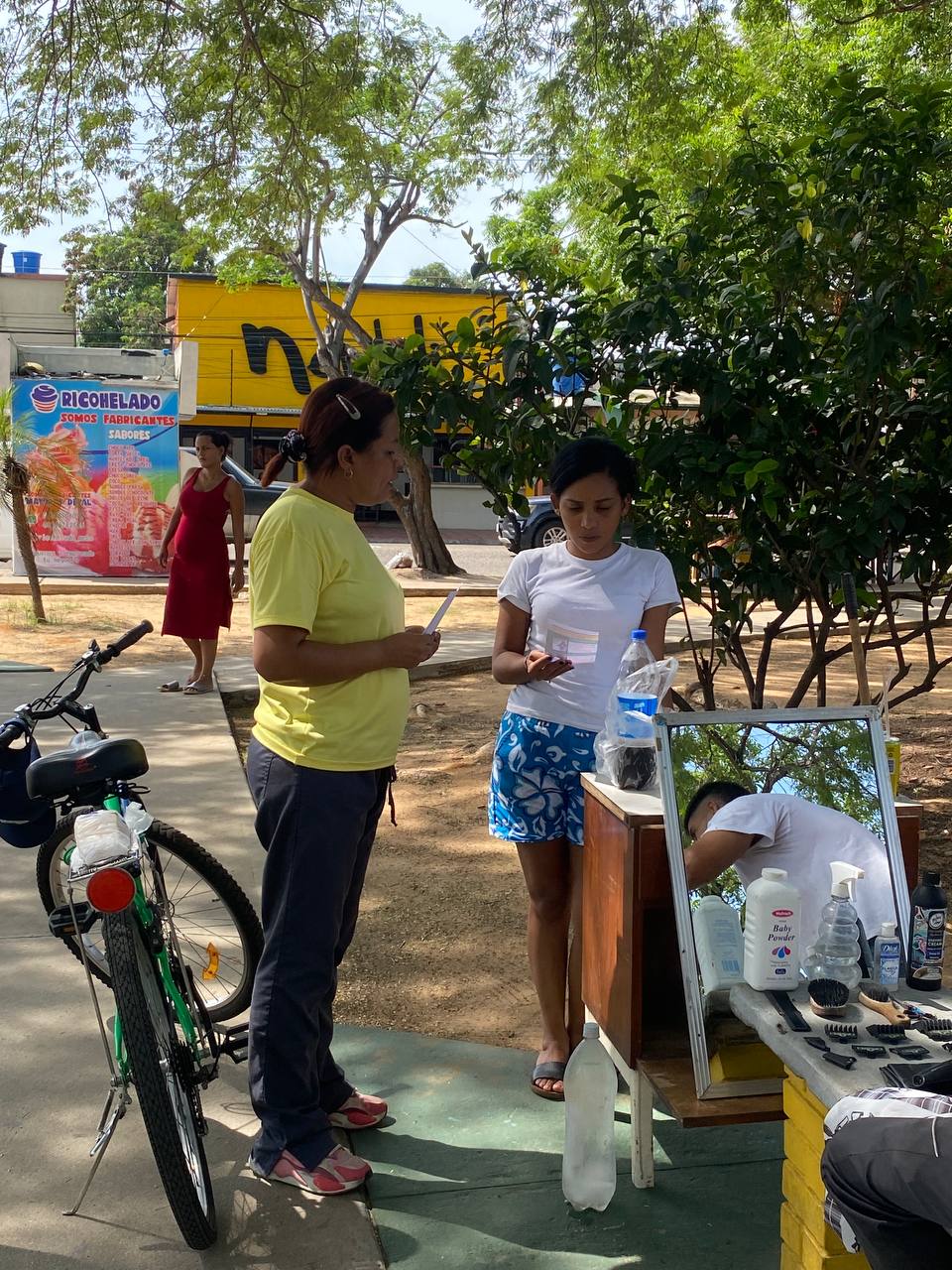 man wearing a black jacket, white shirt, blue jeans, and brown boots, playing a white electric guitar while sitting on an amp